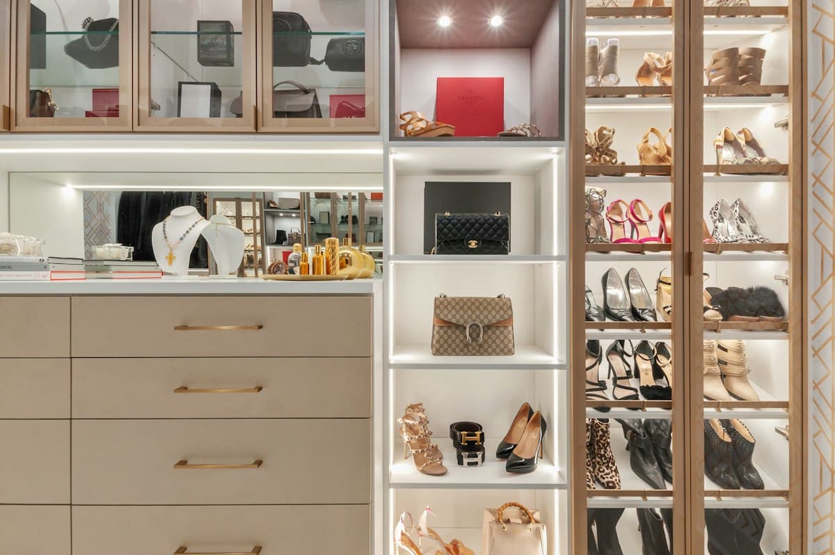 Clóset iluminado con puertas de vidrio, cajones y repisas para zapatos