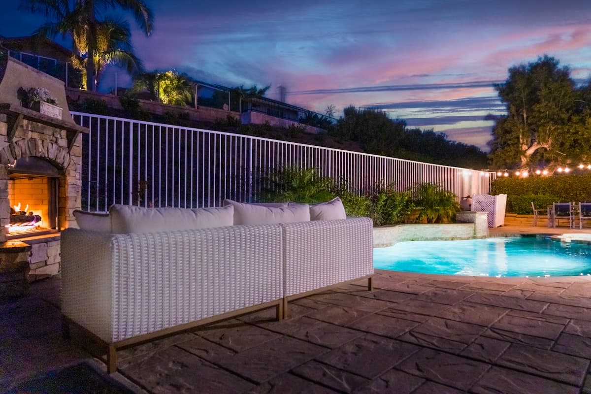 Terraza con muebles de exterior, chimenea y piscina al atardecer