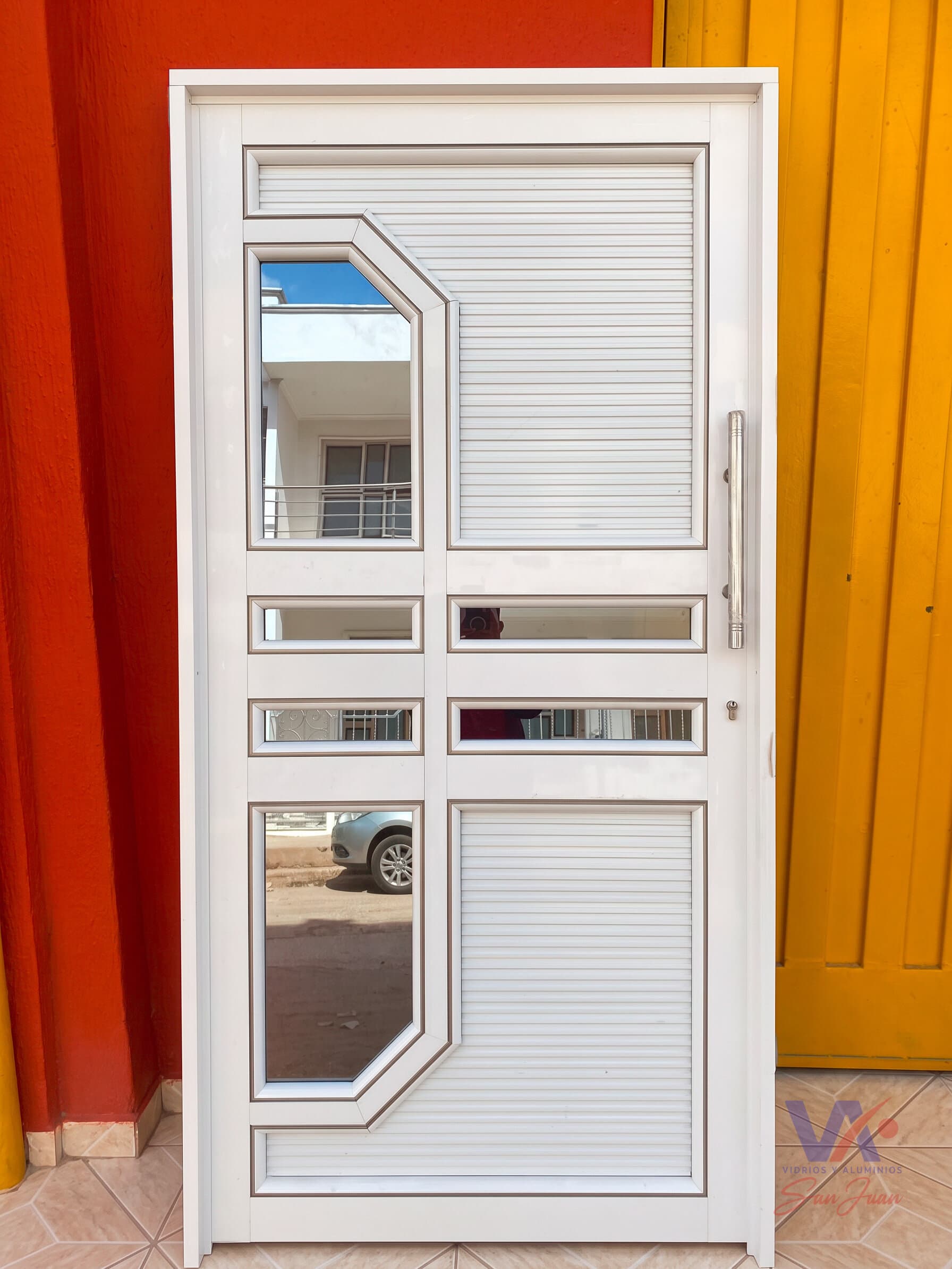 Puerta de aluminio color blanco con paneles acanalados y vidrios de corte diagonal