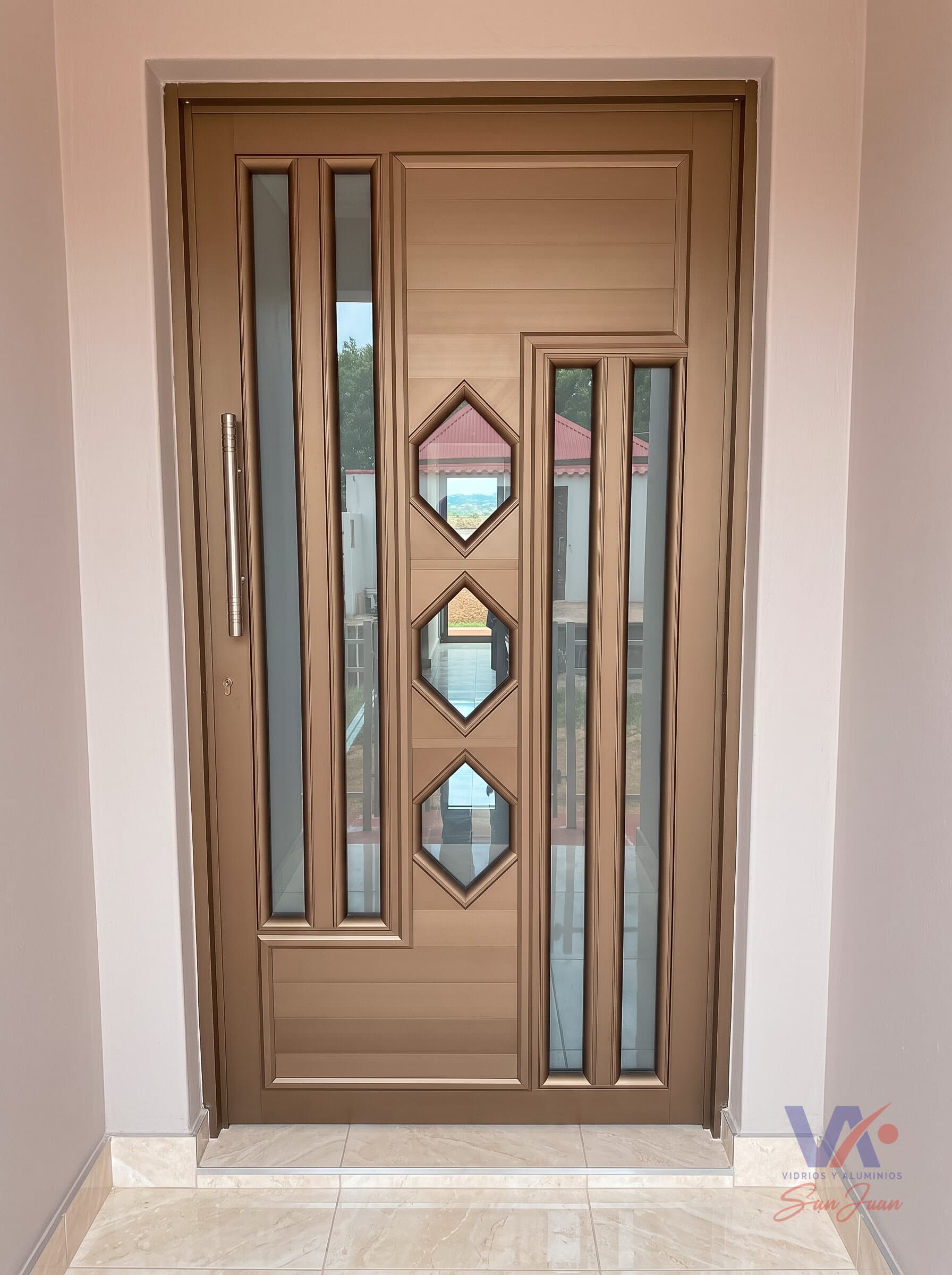 Puerta de aluminio color gris plata con vidrios octogonales y franjas verticales de vidrio, instalada en una vivienda