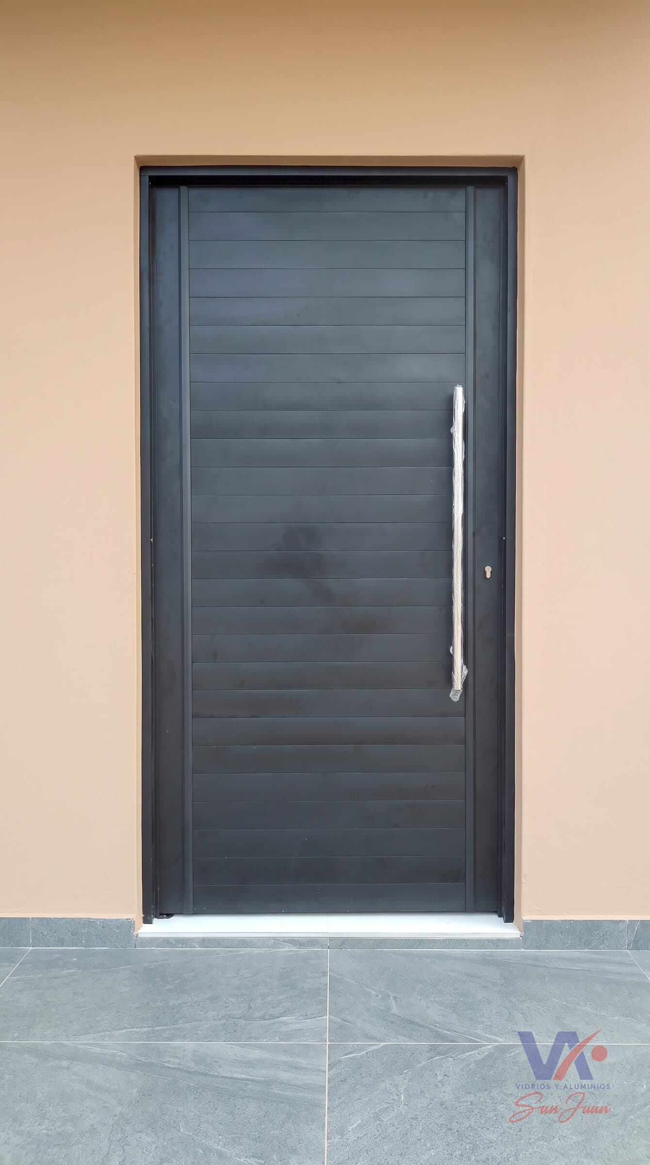 Puerta de aluminio color negro con lamas horizontales y manija vertical larga